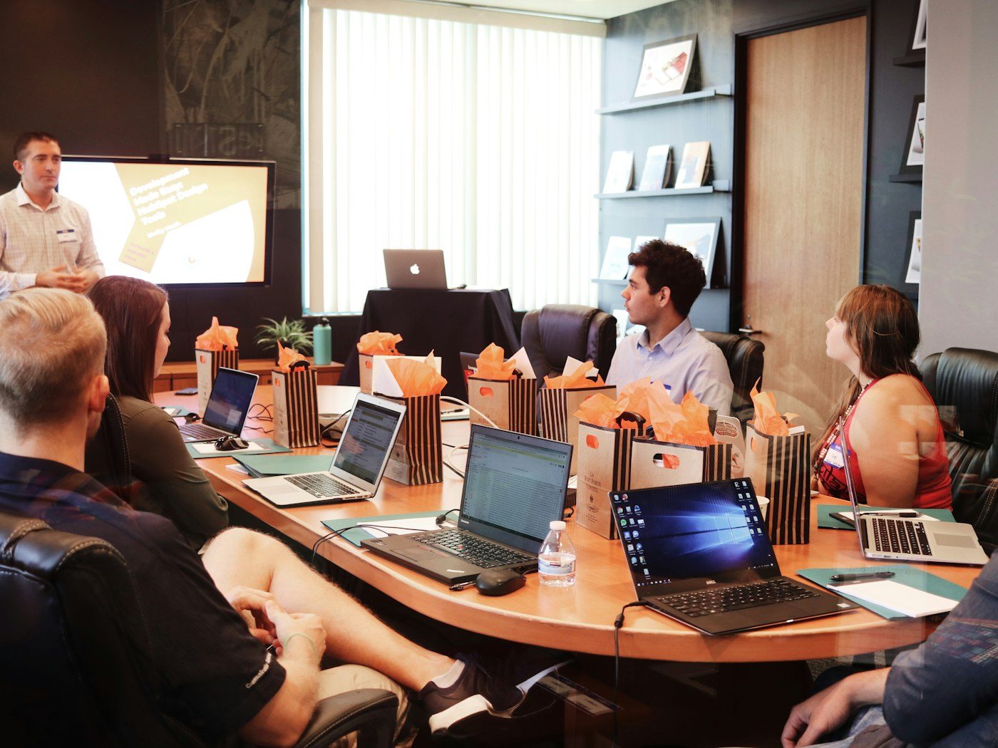 Presenter leading a business meeting with a team at laptops